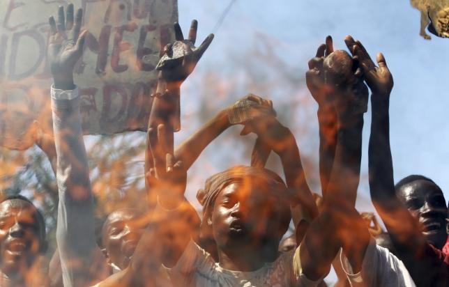 Protesters are seen behind a fire barricade as they chant anti-government slogans before clashing with riot police in Burundi's capital Bujumbura, April 28, 2015.