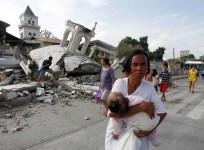 A woman carries her baby past a destroyed church belfry in Tubigon, Bohol on Oct. 16, a day after an earthquake hit central Philippines.