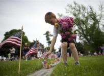 Alex Teeter, 8, places flowers on the grave sites of Battle of Gettysburg soldiers during a ceremony at National Soldier's Cemetery following the Gettysburg Memorial Day parade in Gettysburg, Pennsylvania, May 26, 2014.