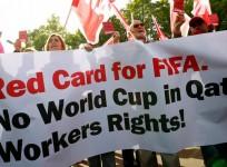 Members of the Swiss UNIA workers union display red cards and shout slogans during a protest