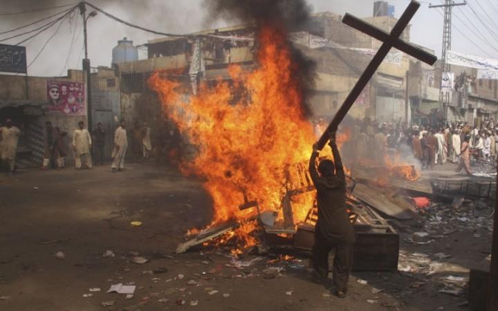 A demonstrator burns a cross during a protest in the Badami Bagh area of Lahore, Pakistan