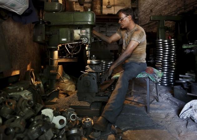 A worker operates a drilling machine as he makes parts for diesel water pumps inside his workshop in Ahmedabad, India, May 4, 2015.