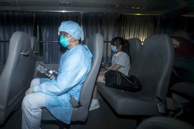 Policemen wearing mask sit in a tent outside Lady MacLehose Holiday Village in Sai Kung, where people who came into close contact with the Korean MERS patient will spend two weeks in quarantine, in Hong Kong, China May 30, 2015.