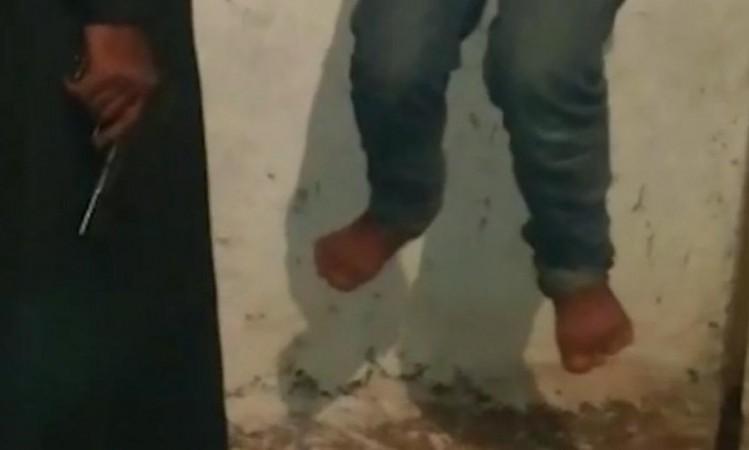 A video grab shows an Isis militant torturing a 14-year old boy