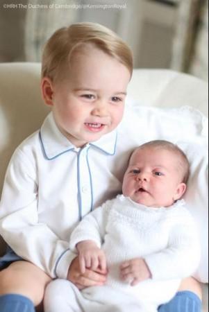 Prince George smiles while holding little sister Princess Charlotte Prince George smiles while holding little sister Princess Charlotte