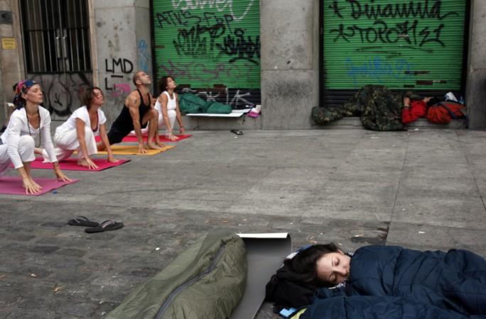 Demonstrators sleep as people practice yoga at Madrid's Puerta del Sol.