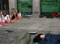 Demonstrators sleep as people practice yoga at Madrid's Puerta del Sol.