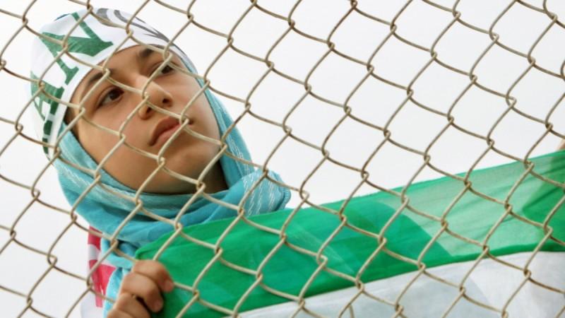 An Iranian woman watches the practice session of Iran's national soccer team from behind a fence because women are banned from entering the stadium at Azadi (Freedom) sports complex in Tehran, Iran, May 21, 2006.