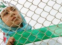 An Iranian woman watches the practice session of Iran's national soccer team from behind a fence because women are banned from entering the stadium at Azadi (Freedom) sports complex in Tehran, Iran, May 21, 2006.