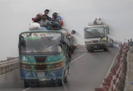 An overcrowded bus drives on a bridge while on a highway near Dhaka