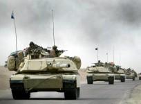 A convoy of US Army 3rd Infantry M1A1 Abrams tanks cross the Euphrates river as black smoke rises after an explosion as hundreds of armored vehicles push towards the outskirts of Baghdad on April 6, 2003.