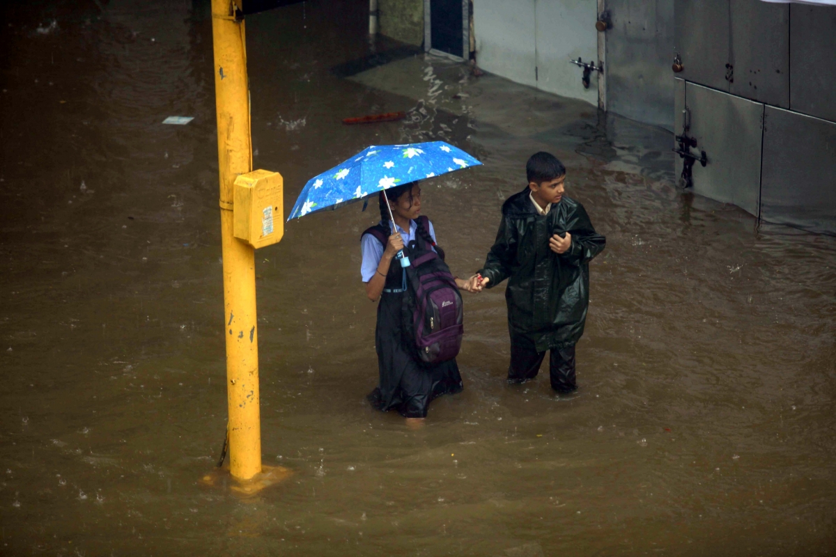 School students wade througha water-logged road of Mumbai on June 19, 2015. Mumbai and surroundings were paralysed as heavy rains lashed these areas since last evening. Mumbai Rain