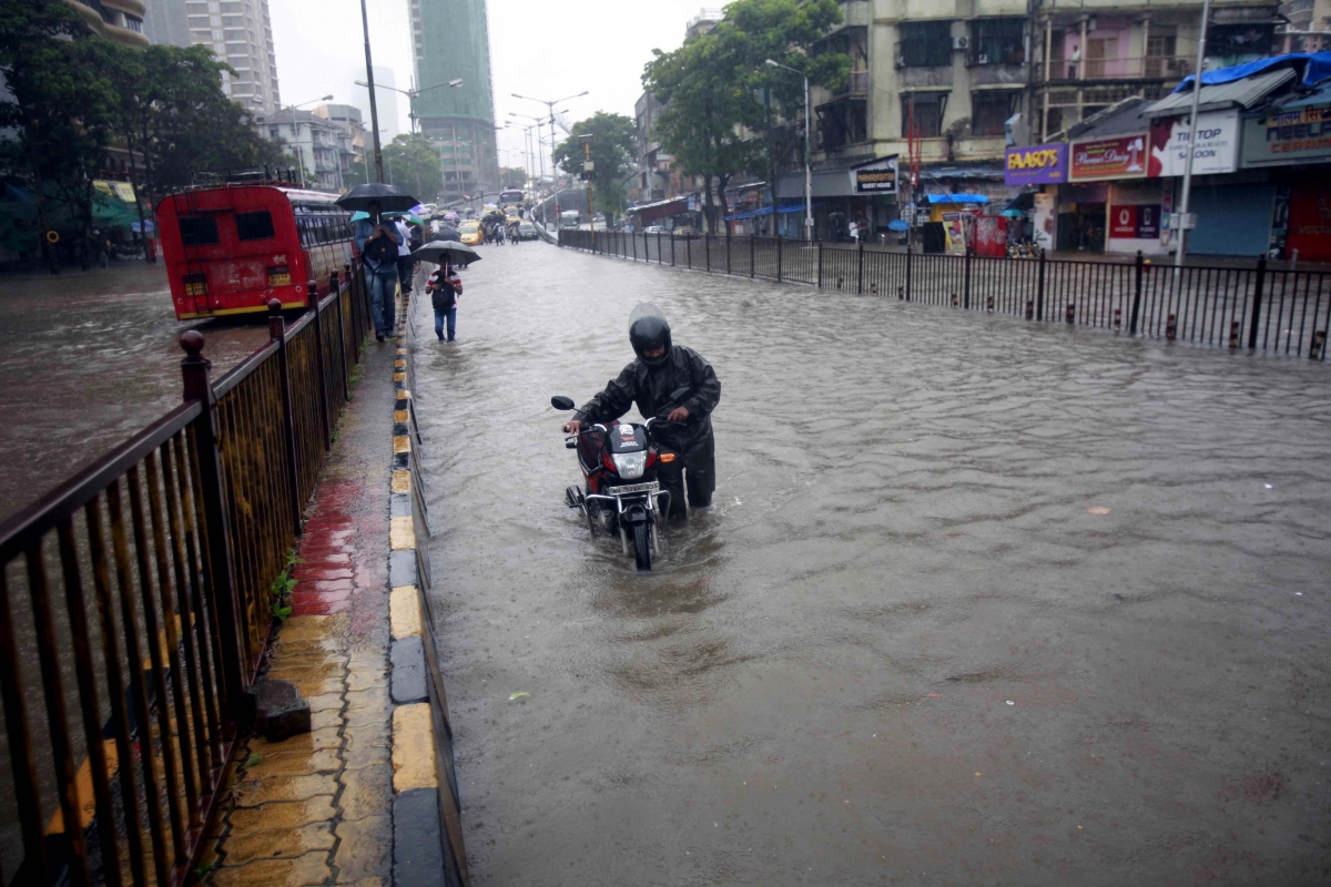 A biker pulls his bike on a water-logged road of Mumbai on June 19, 2015. Mumbai and surroundings were paralysed as heavy rains lashed these areas since last evening Mumbai Rain