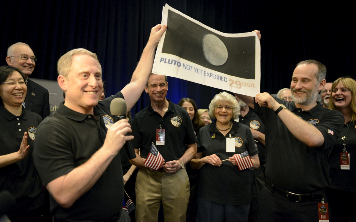 NASA Principal Investigator for New Horizons mission Alan Stern (L) and Co-Investigator Will Grundy (R) hold up an enlarged, out-dated U.S. postage stamp with the ''NOT YET'' crossed out, during the celebration of the spacecraft New Horizons flyby of Pluto New Horizons