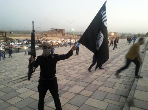 A militant holds an Isis flag on a street in the city of Mosul on 23, June, 2014. isis militant waves flag