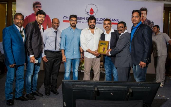 Chiranjeevi and Ram Charan giving mementos to fans