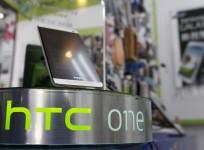 An HTC One smartphone is displayed in a mobile phone shop