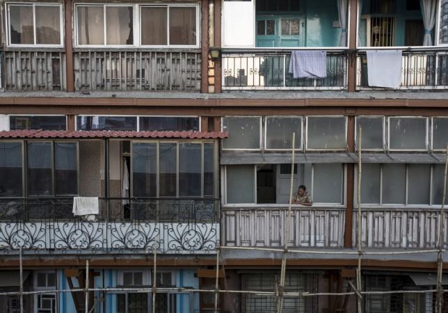 A woman looks out of a window of an apartment in south Mumbai March 15, 2015. The cost for buying a 600 square feet (55 square meters) one-bedroom apartment in this building is around 20,000 Indian rupees per square feet ($ 320) or 12,000,000 Indian rupee