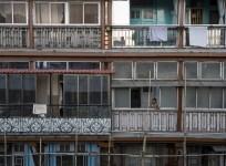 A woman looks out of a window of an apartment in south Mumbai March 15, 2015. The cost for buying a 600 square feet (55 square meters) one-bedroom apartment in this building is around 20,000 Indian rupees per square feet ($ 320) or 12,000,000 Indian rupee