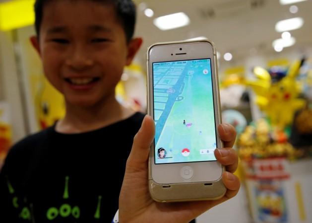 A kid playing an AR game In Picture: A boy poses with a mobile phone displaying the augmented reality mobile game