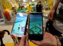 Men pose with their mobile phone displaying the augmented reality mobile game "Pokemon Go"