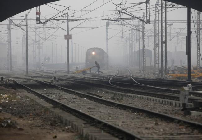 rail stocks wagons engineering texmaco kalindee titagarh rail nirman indian railways prabhu track renewal expansion infra push govt A labourer pushes a handcart past a train as he crosses railway tracks on a foggy and cold winter morning in New Delhi Janu