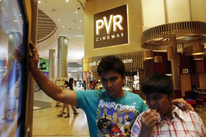 The Bombay Stock Exchange (BSE) has sought explanation from PVR to a media report of stake buy by Chinese conglomerate Wanda Group. In Picture: Cinema-goers watch a movie trailer at a PVR Multiplex in Mumbai November 10, 2013 (representational image). pvr share price screen expansion profit revenue ticket price box office collection china chinese wanda group stake sale buy ok fine let it be Dalian Wanda Group screen count multiplexes in india sensex stocks gains movie film watching queue