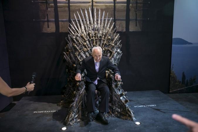 Shimon Peres smiles as he sits on the Iron Throne during the opening of the Game of Thrones exhibition in Tel Aviv, April 2015. Shimon Peres