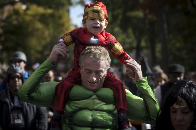 Pictured: Child dressed as Ironman rides on an adult's shoulders who is dressed up as the Hulk on Halloween. Halloween