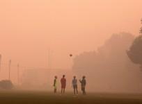 Boys play football in a public park on a smoggy morning in New Delhi