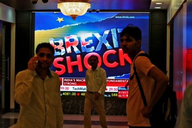 People stand past a a screen displaying news of markets update inside the Bombay Stock Exchange (BSE) building in Mumbai, India, June 24, 2016. Bilateral trade between India and Britain is poised to decline due to a fall in the British pound and Brexit woes, according to Ficci. theresa may modi india visit trade bilateral brexit pound sterling decline investment ficci didar singh meetings talks discussions agreements deals lecture indian it companies tata steel tcs maruti mahindra