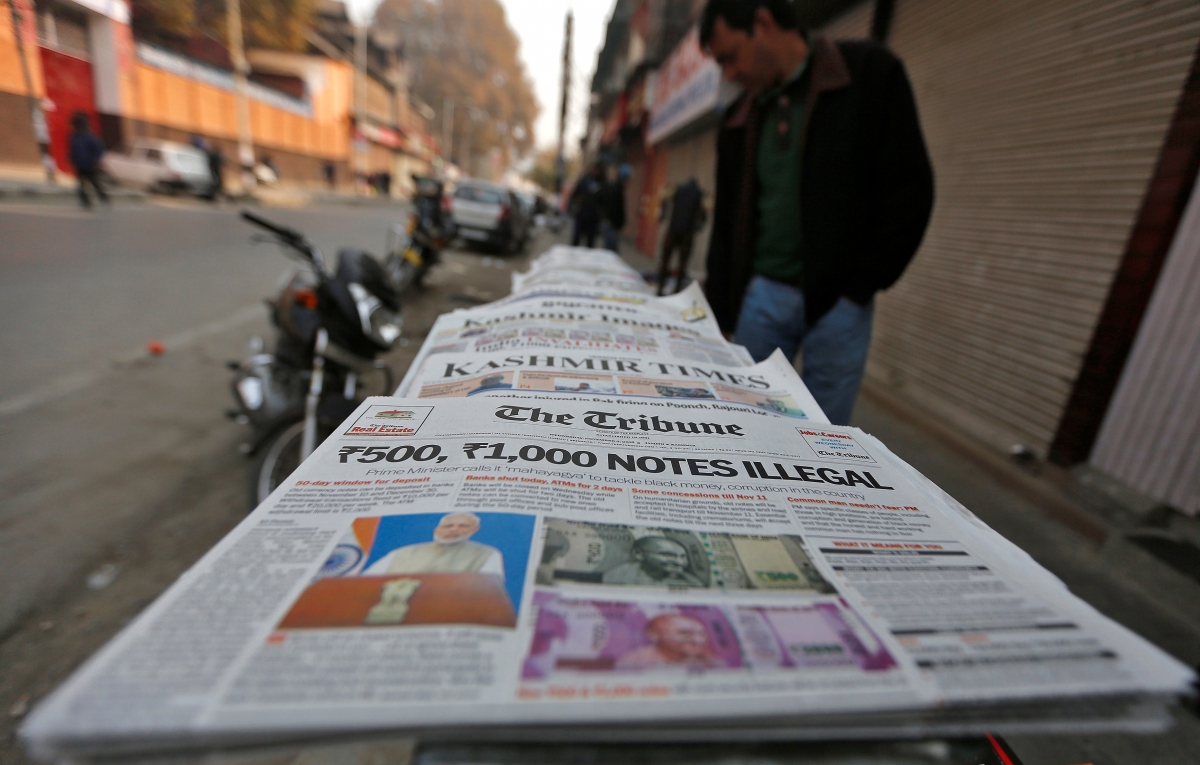 A man looks at newspapers with cover stories on withdrawal of Indian 500 and 1,000 rupee notes from circulation, on a pavement in Srinagar November 9, 2016. ban rs 500 note rs 1000 rbi modi pm announcement surprise replacement black money sit stock markets us elections