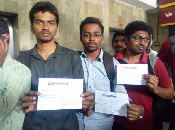 Students Dhanush V, Vinod Kumar K and Mounesh J stand in line with their forms, ready to get their currency notes exchanged. Queue
