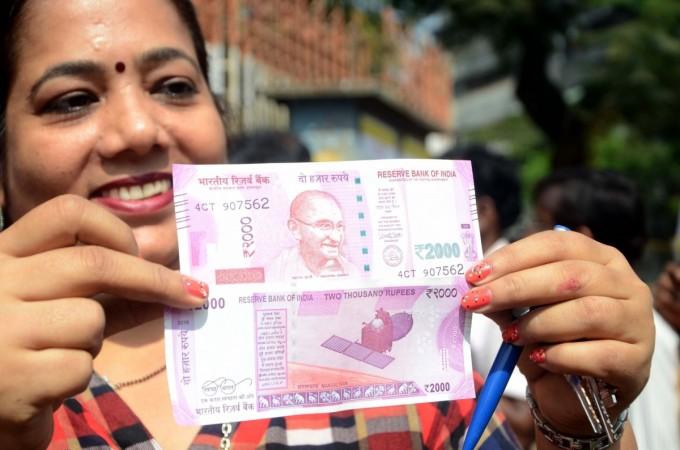 A woman shows the new 2000 rupee currency note in Mumbai on Nov. 10, 2016. ban on currency rs 500 1,000 1000 note modi rbi demonetization black money scrapped new notes 2000 new 500 coins legal tender rbi sit narendra