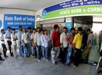 People wait to withdraw money from ATMs