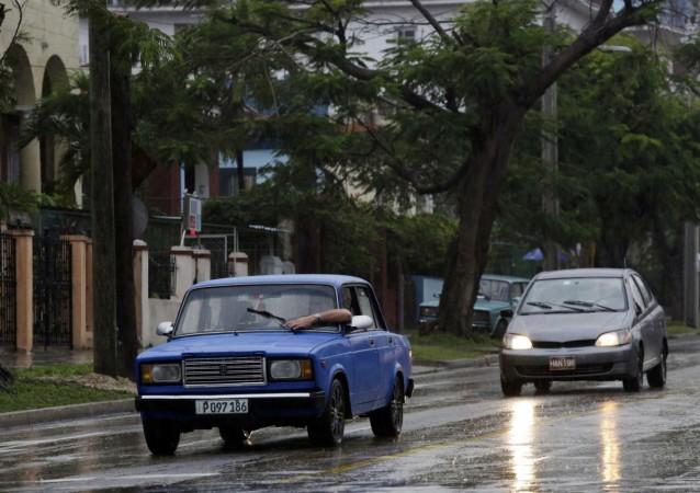 A man tries to adjust the windshield wiper of his Lada while driving in the rain in Havana February 8, 2015. The former Soviet Union began exporting its cheaply built models to Cuba in the 1970s until production began to peter out a decade ago. Very little evidence of Soviet influence remains in Cuba, except the spunky little Russian-made Lada cars, famous for rattling chassis but sturdy engines. fidel castro obama economy cuban tourism beaches loved ones Caribbean islands peso diplomatic relations war cold war russia ussr satellite cuban missile crisis soviet russia