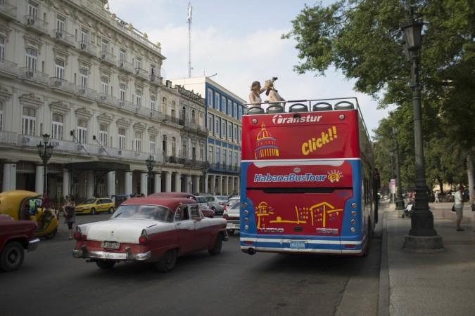 Tourists take pictures atop a double decker sightseeing bus in Havana January 15, 2015. The United States announced sweeping new rules that will significantly ease sanctions on Cuba, opening up the communist-ruled island to expanded U.S. travel, trade and financial activities. fidel castro obama economy cuban tourism beaches loved ones Caribbean islands peso diplomatic relations war cold war russia ussr satellite cuban missile crisis soviet russia