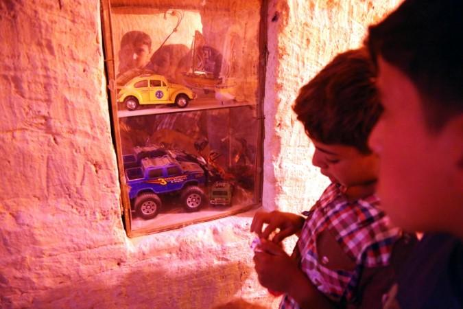In picture: Two children look through a show window inside the Land of Childhood, an underground playground in a besieged area in Syria. Syria