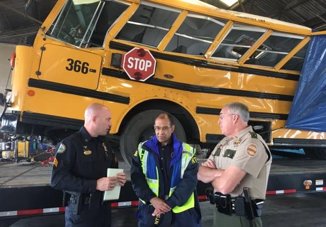 Christopher Hart (C), chairman of the National Transportation Safety Board, speaks with Chattanooga Police and Tennessee Highway Patrol officers while viewing the wreck of a school bus in which several children were killed, at a depot in Chattanooga, Tennessee Tennessee bus crash