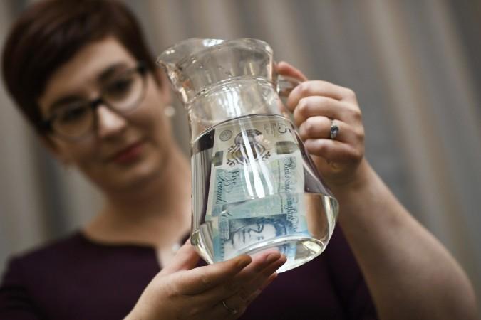Bank of England Museum curator Jenni Adam, shows off the waterproof properties of the new polymer five pound note during an event at the Bank of England in central London, Britain September 6, 2016. plastic note polymer note rbi bank of england tender printing demonetisation counterfeit BRBNMPL SPMCI