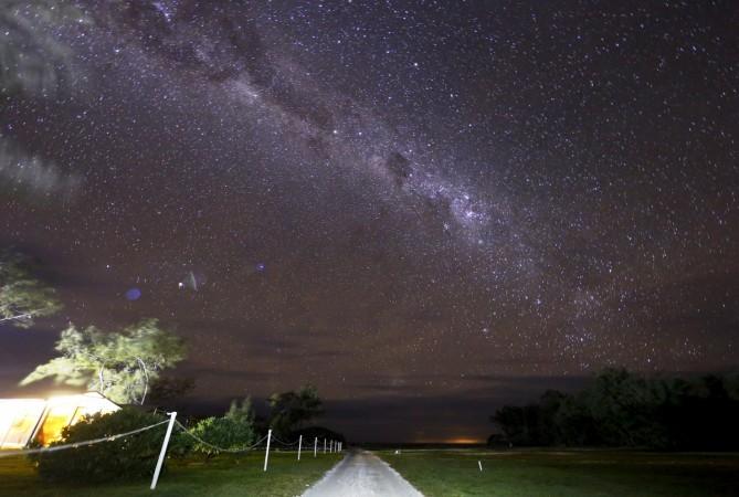 The Milky Way can be seen in the sky above a path and huts on Lady Elliot Island