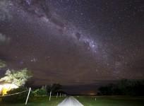 The Milky Way can be seen in the sky above a path and huts on Lady Elliot Island