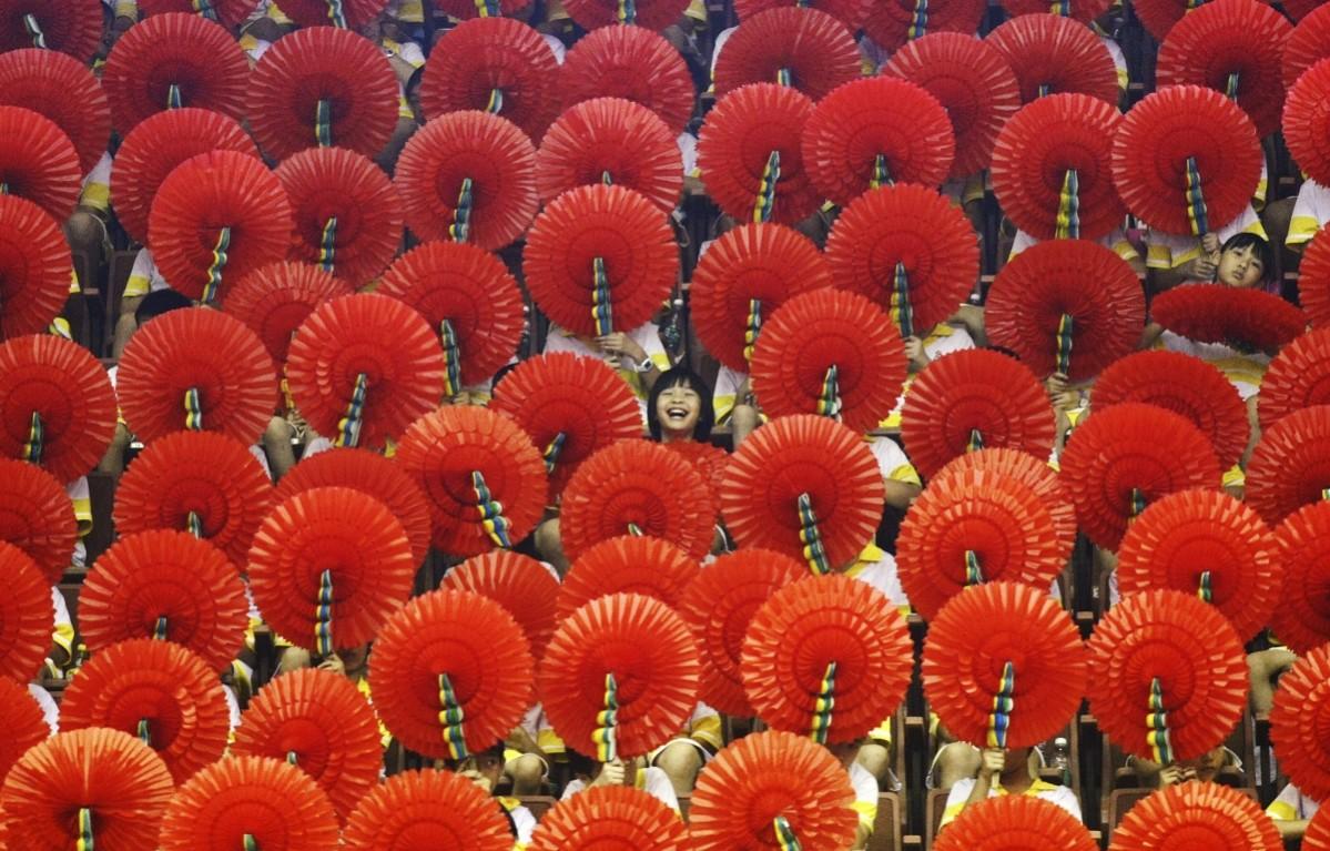 A girl laughs as she sits among hand fans during a mass performance at a children's martial arts fair in Foshan, Guangdong province, China A girl laughs as she sits among hand fans during a mass performance at a children's martial arts fair in Foshan, Guangdong province