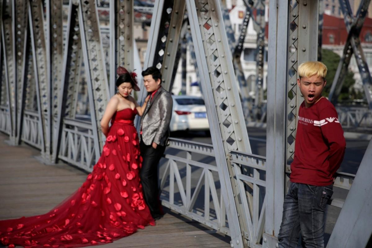 A bored wedding photographer's assistant yawns on a street in Shanghai, China, as the couple pose for their wedding album A wedding photographer's assistant yawns on a street in Shanghai, China