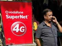 A man speaks on his mobile phone next to a Vodafone advertisement in Kolkata
