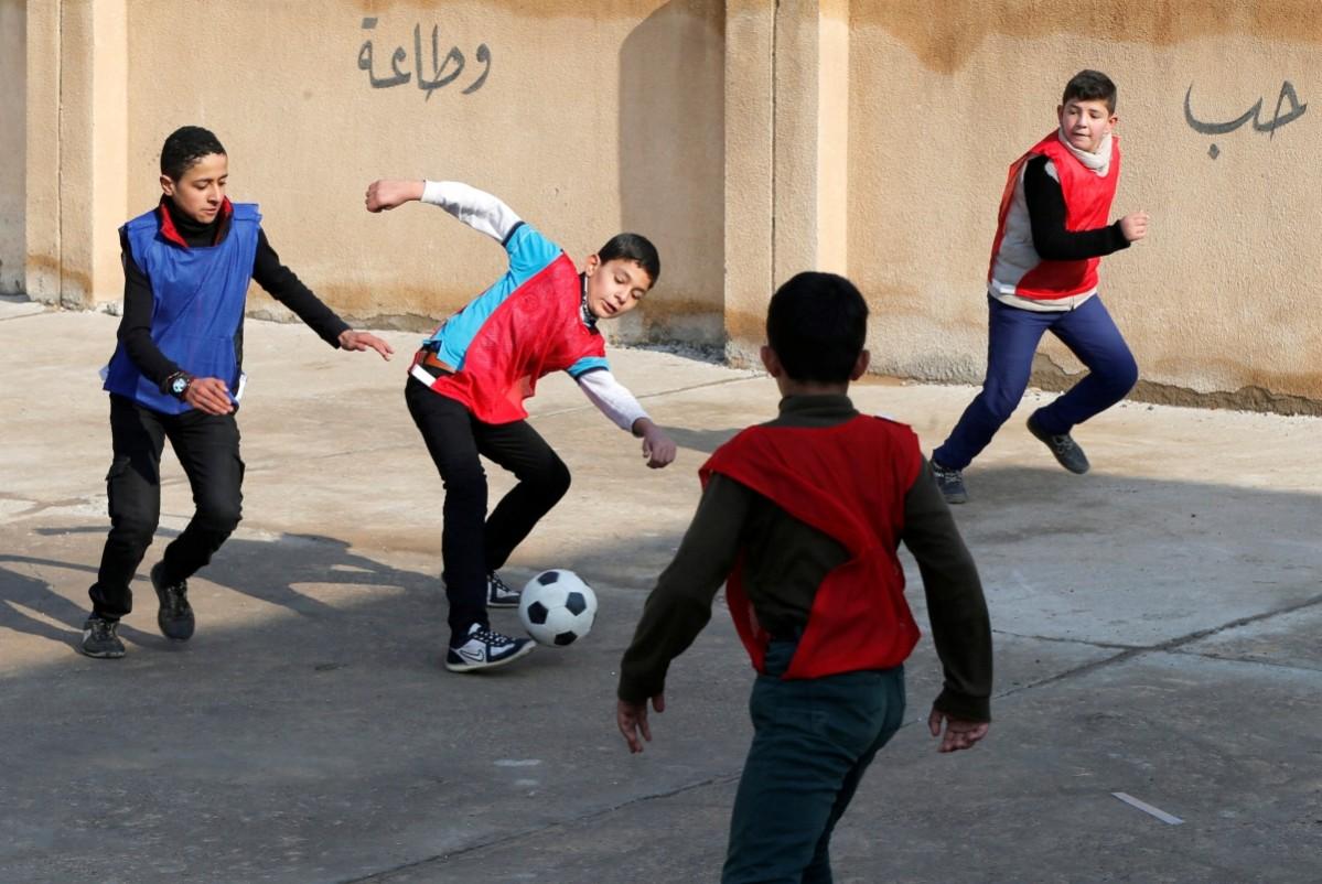 In another school in east Mosul, young boys play football in after they registered. The writing on the wall, from the siege by the ISIS, reads Football after ISIS extremists are defeated in Iraq