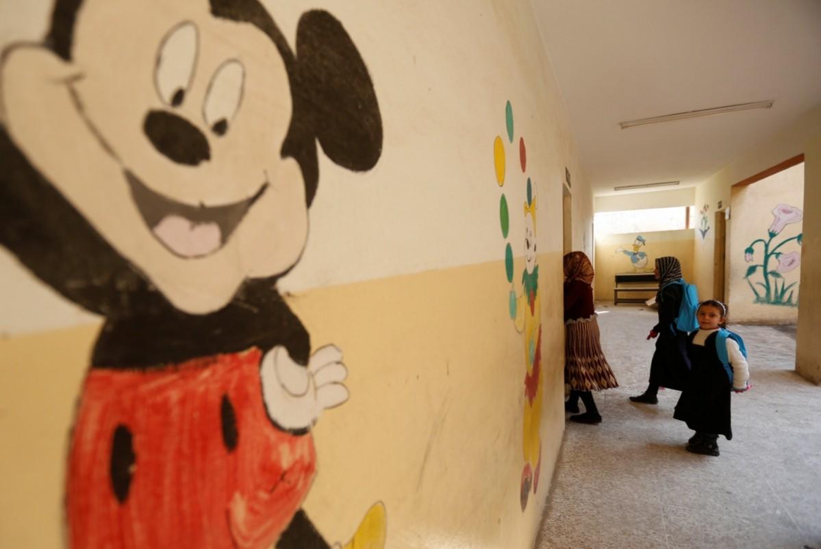 Under the ever-smiling eyes of Mickey Mouse, schoolchildren walk along a corridor in east Mosul. Reuters ISIS-affected children return to school in east Mosul, Iraq