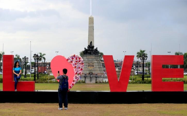 People take pictures of a "LOVE" display day before Valentine's Day in Rizal park