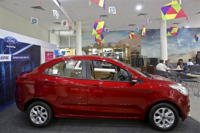 Customers sit near Ford's new Figo Aspire car on display at a showroom in New Delhi, India, August 11, 2015 car exports from india, car exports in feb 2017, ford exports, maruti suzuki exports, hyundai exports