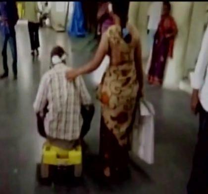 Raju pushing around on his son's tricycle while his wife Santoshi helps him Raju pushing around on his son's tricycle while his wife Santoshi helps him